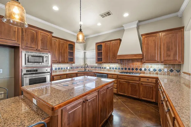 a kitchen with stainless steel appliances granite countertop a sink a stove and a refrigerator