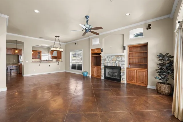 a view of a livingroom with a fireplace a chandelier and windows