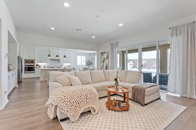 a kitchen with a stove a sink a kitchen island with chairs and wooden floor
