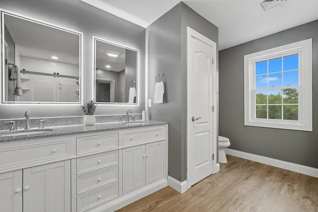 a bathroom with a granite countertop sink mirror and next to a window
