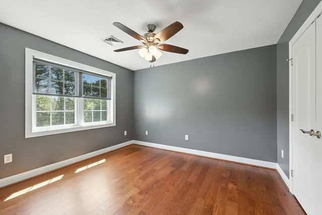 an empty room with a window and ceiling fan