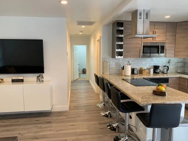 a kitchen with stainless steel appliances kitchen island granite countertop a sink and a stove top oven with wooden floor