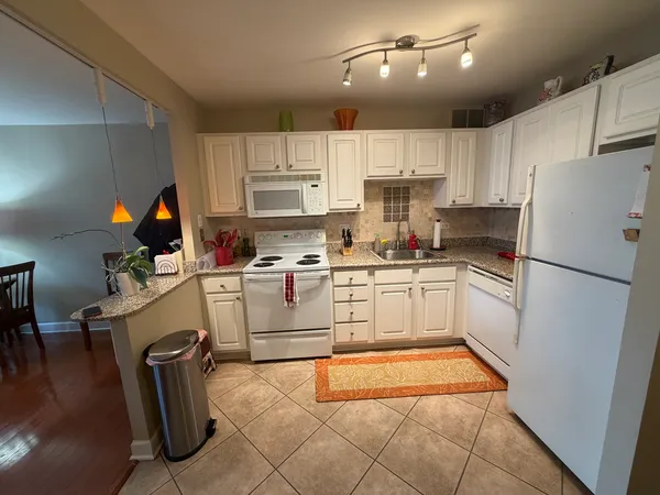 a kitchen with white cabinets and refrigerator