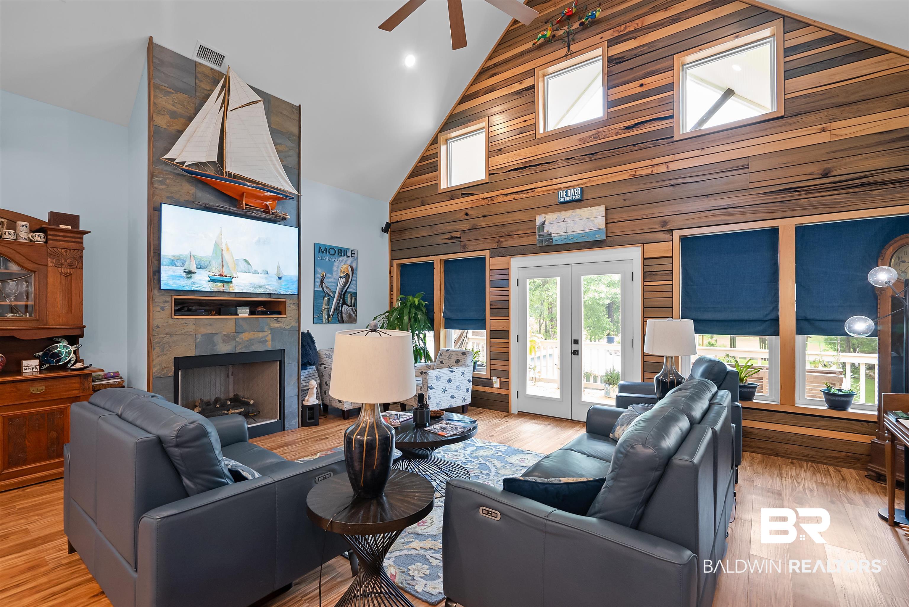 7266 Franklin Road Foley, AL 36535 - Photo 17 of 64 Vaulted ceiling living area featuring a stone-clad fireplace, wood-finish flooring, and a natural wood accent wall