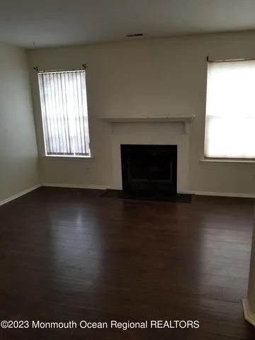 an empty room with wooden floor a fireplace and windows