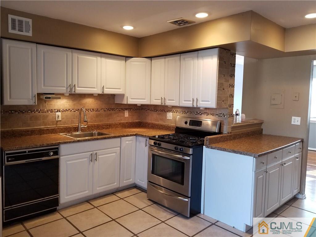 197 Evergreen Road, Unit 3B Edison, NJ 08837 - Photo 8 of 20 a kitchen with granite countertop a stove top oven microwave and cabinets