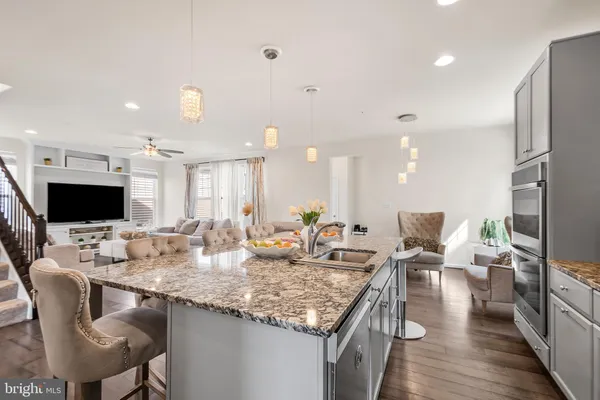 a kitchen with granite countertop kitchen island stainless steel appliances refrigerator stove dining table and chairs