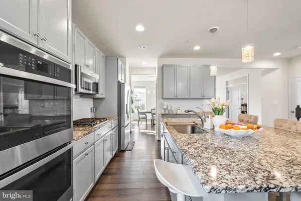 a kitchen with stainless steel appliances kitchen island granite countertop a stove a sink and a refrigerator