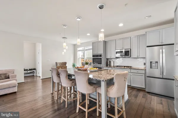 a kitchen with stainless steel appliances a dining table chairs refrigerator sink and cabinets