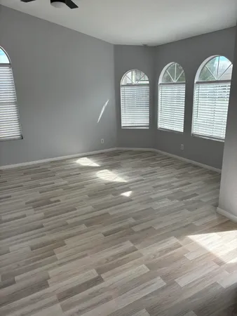 a view of empty room with wooden floor and fan