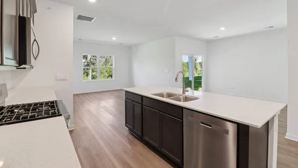 a kitchen with stainless steel appliances a sink stove and wooden floor
