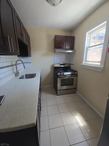a kitchen with granite countertop a stove a sink and a microwave