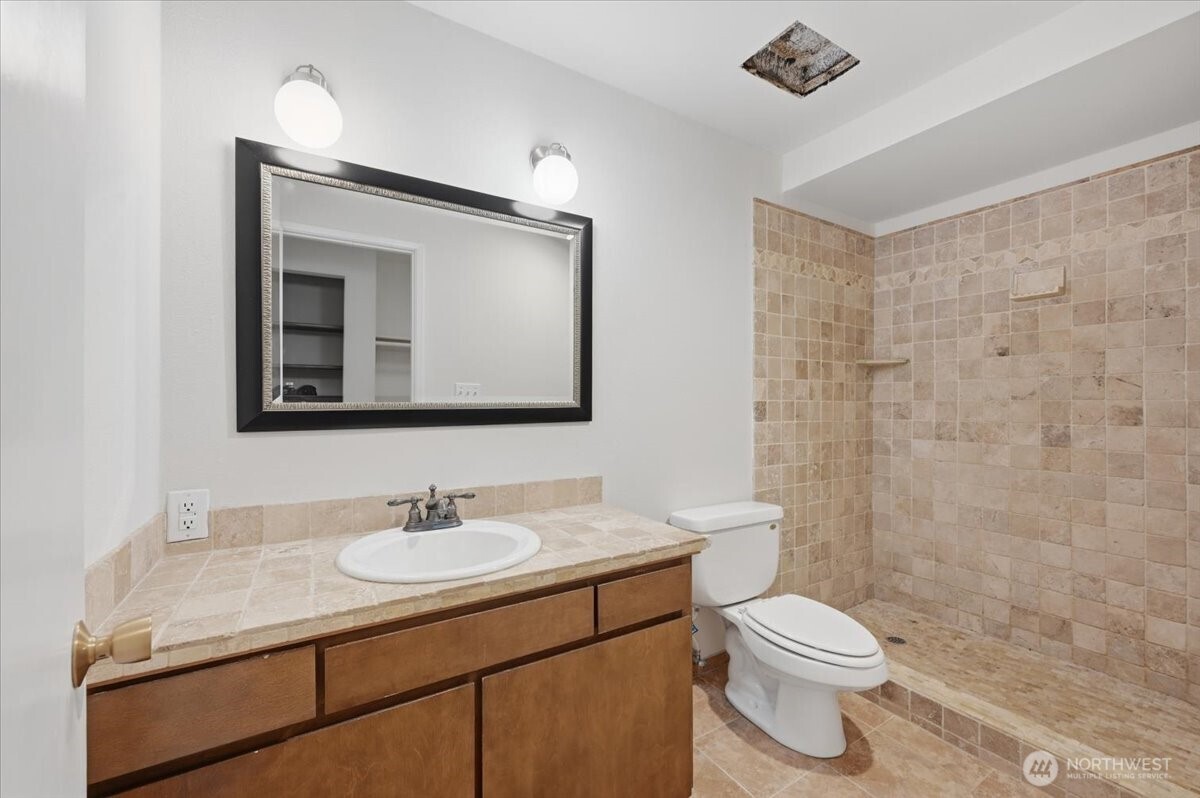 8516 196th Street Southwest, Unit 204 Edmonds, WA 98026 - Photo 15 of 16 a bathroom with a granite countertop sink a toilet and a mirror