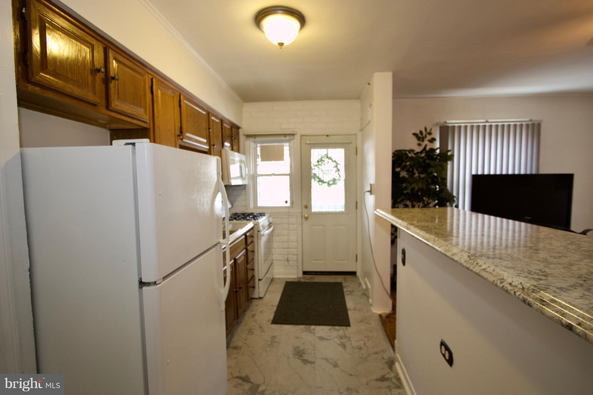 134 North Culver Street Baltimore, MD 21229 - Photo 13 of 30 a kitchen with a refrigerator a stove and wooden floor