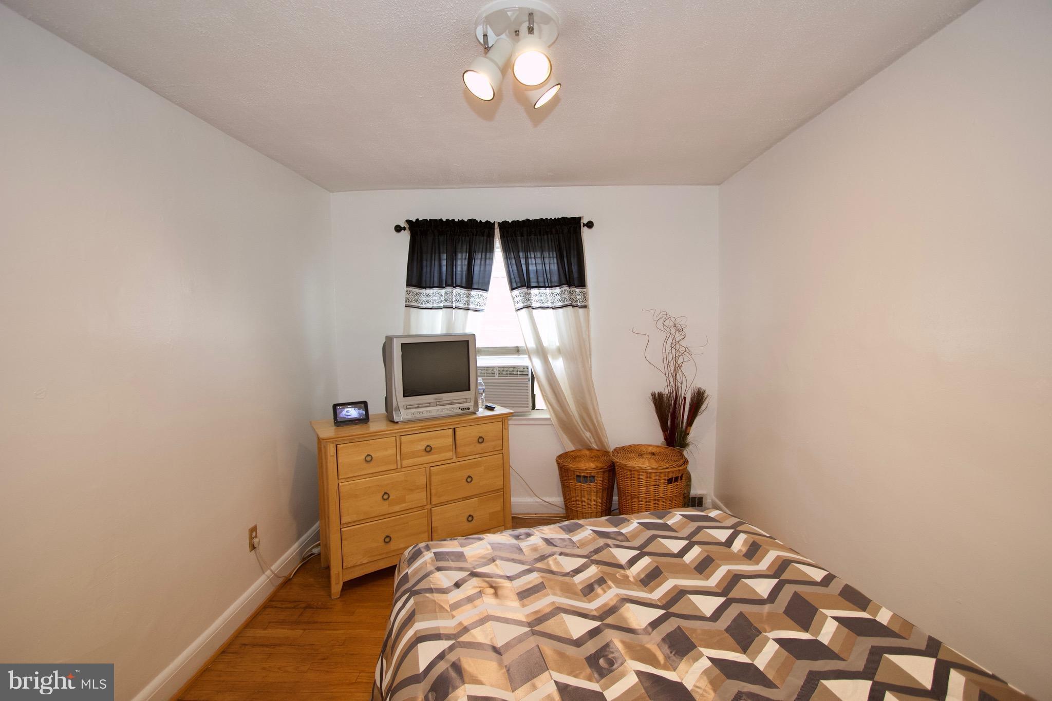 134 North Culver Street Baltimore, MD 21229 - Photo 17 of 30 a bedroom with a bed and a flat tv screen on dresser