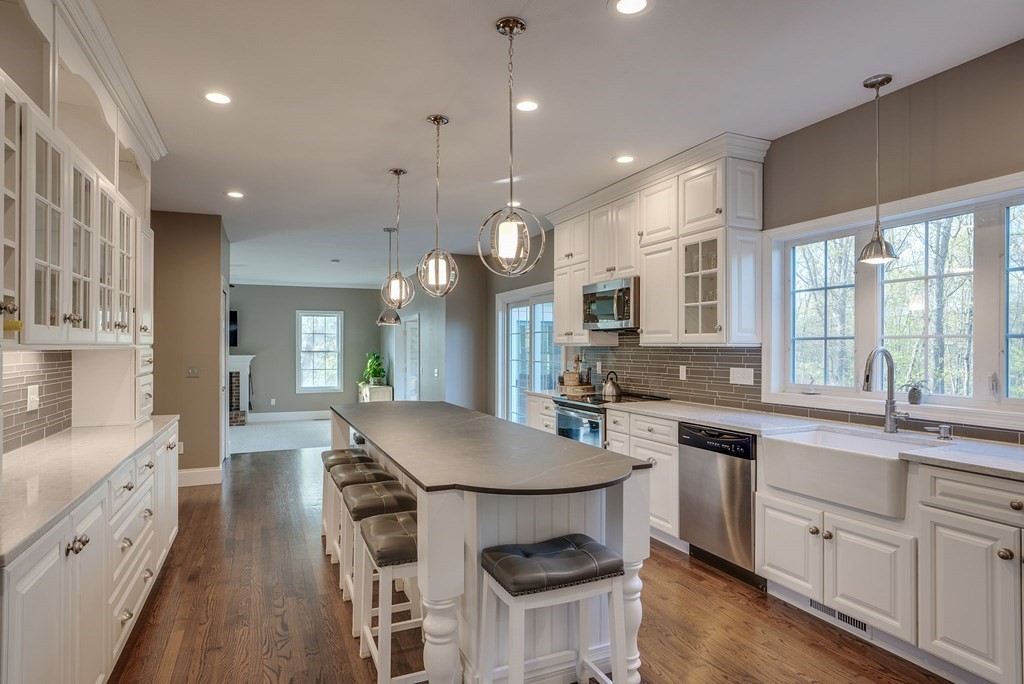 40 Partridge Road Windham, NH 03087 - Photo 15 of 42 a kitchen with stainless steel appliances kitchen island granite countertop a stove a sink dishwasher a refrigerator and white cabinets with wooden floor
