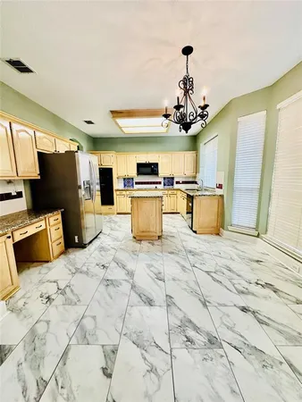 a large kitchen with stainless steel appliances kitchen island granite countertop a stove top oven a sink dishwasher and white cabinets with wooden floor