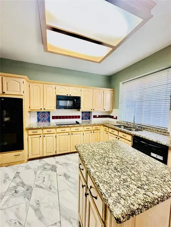 a kitchen with a sink stainless steel appliances wooden floor and a window