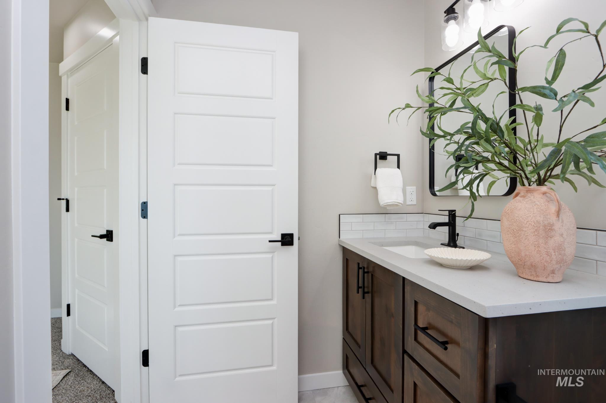 848 North 5th Street Nyssa, OR 97913 - Photo 18 of 49 Bathroom featuring a dark wood-finish vanity with a light countertop, white subway tile backsplash, and a framed mirror with a wall-mounted light fixture