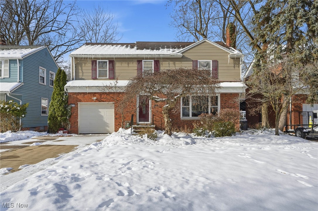 Traditional-style home featuring brick siding, a chimney, and an attached garage