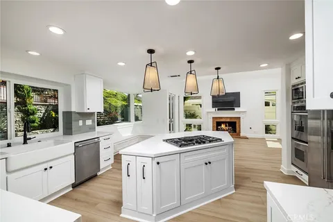 a kitchen with stainless steel appliances kitchen island granite countertop a sink stove refrigerator and cabinets