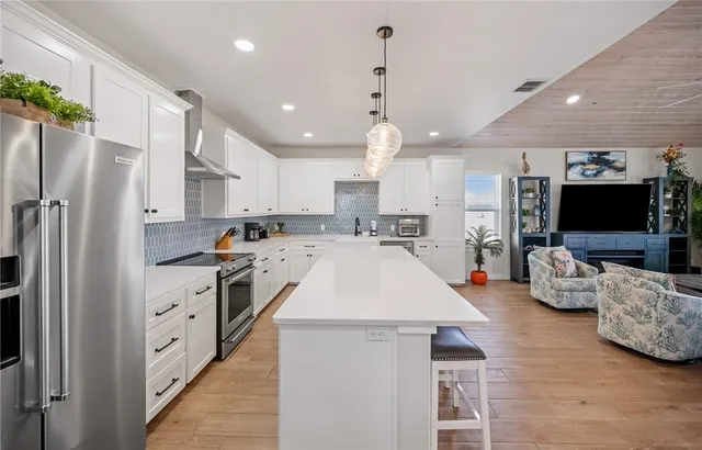 a large kitchen with stainless steel appliances kitchen island granite countertop a refrigerator and a stove top oven