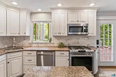 a kitchen with granite countertop a stove a sink and a microwave