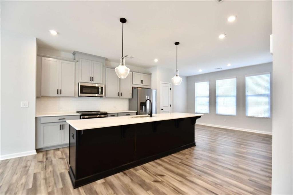 809 Cameron Trail Acworth, GA 30102 - Photo 6 of 38 a kitchen with stainless steel appliances a sink stove and white cabinets with wooden floor