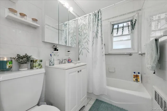 a white bath tub sitting next to a white sink and cabinets