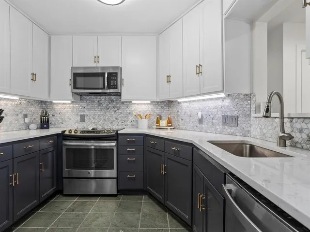 a kitchen with white cabinets stainless steel appliances and sink