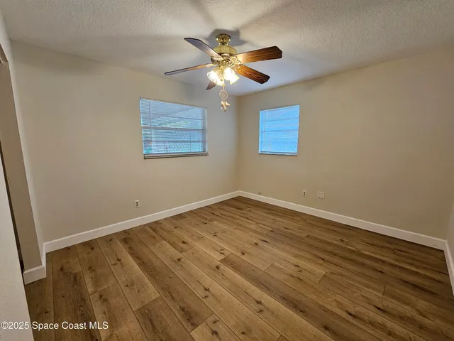 an empty room with wooden floor and ceiling fan