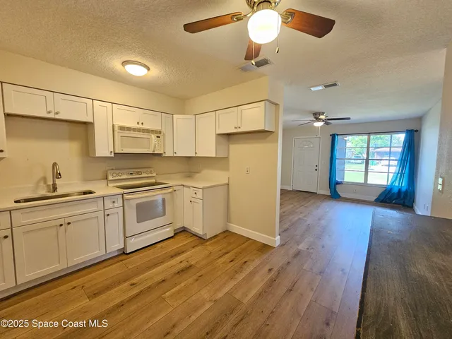 a kitchen with wooden floors and white cabinets