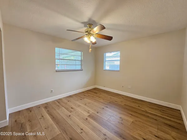 a view of an empty room with window and wooden floor