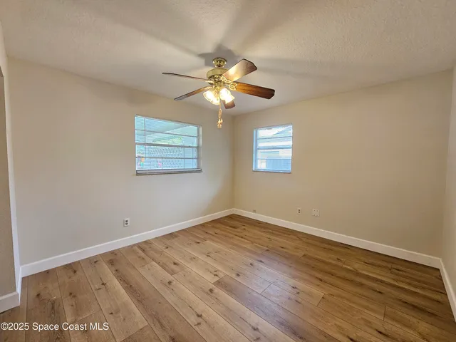 a view of an empty room with window and wooden floor