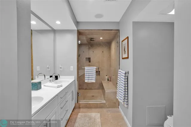 a bathroom with a double vanity sink and mirror with shower