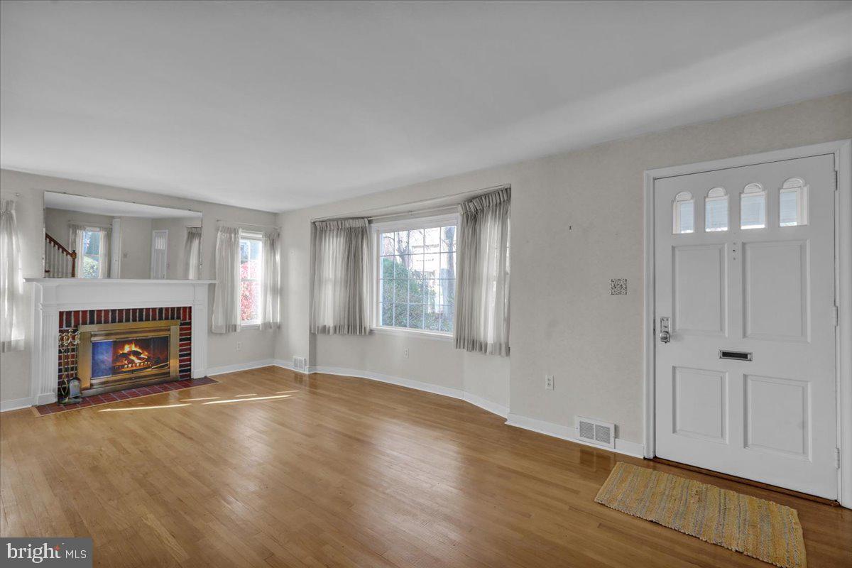 1510 Garfield Avenue Wyomissing, PA 19610 - Photo 2 of 26 an empty room with wooden floor fireplace and windows