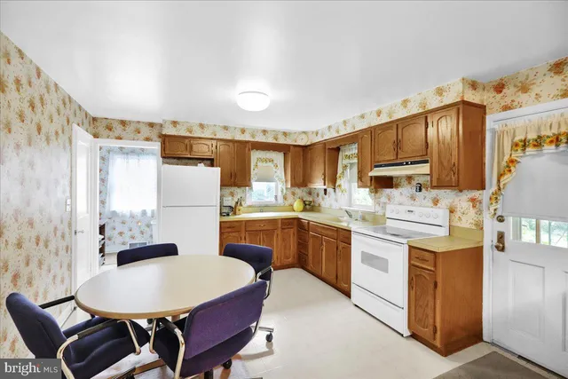 a kitchen with kitchen island a stove a sink a dining table and chairs