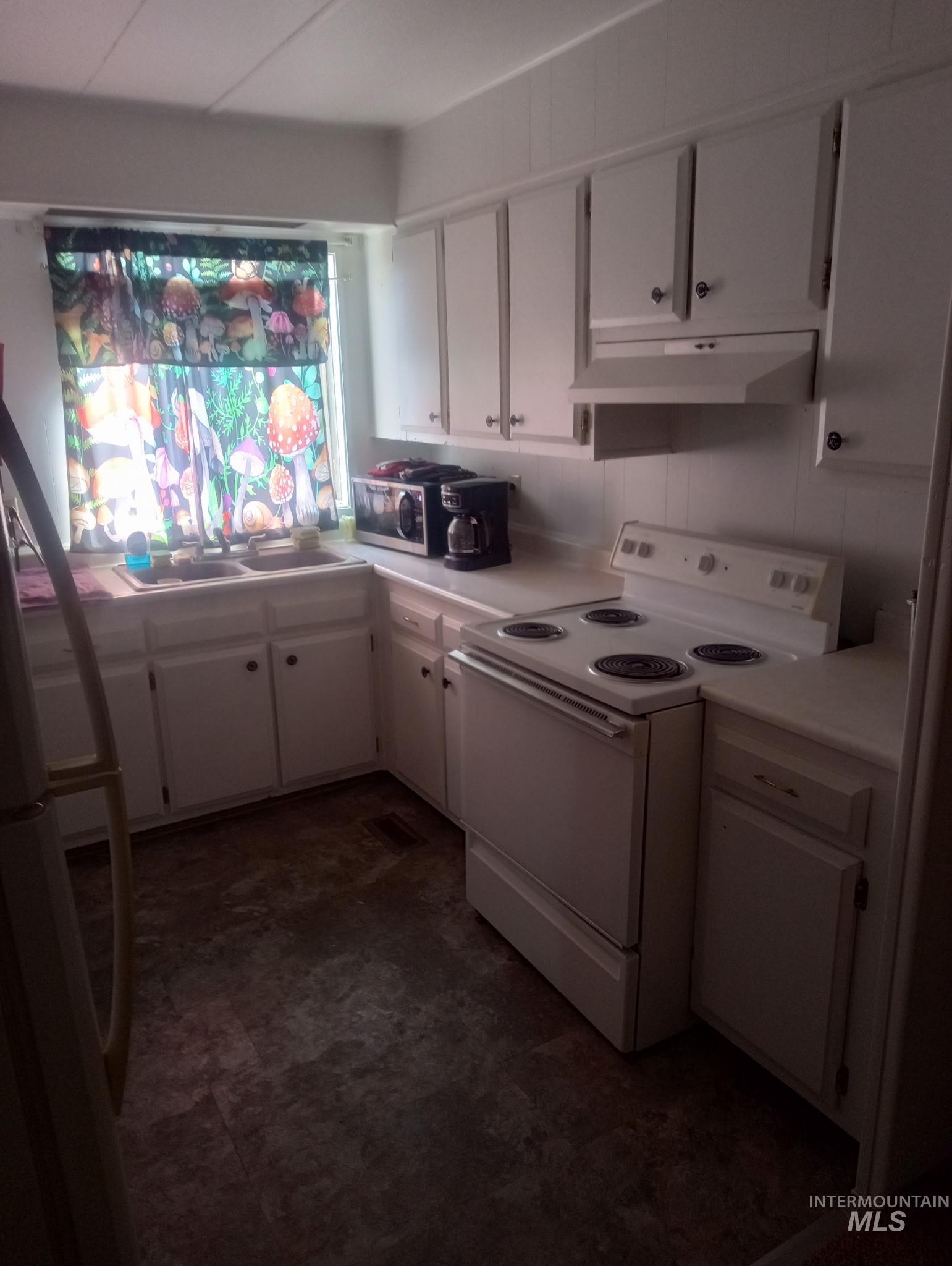 749 Ritter Avenue Vale, OR 97918 - Photo 20 of 28 Kitchen with white appliances, white cabinetry, light countertops, and under cabinet range hood