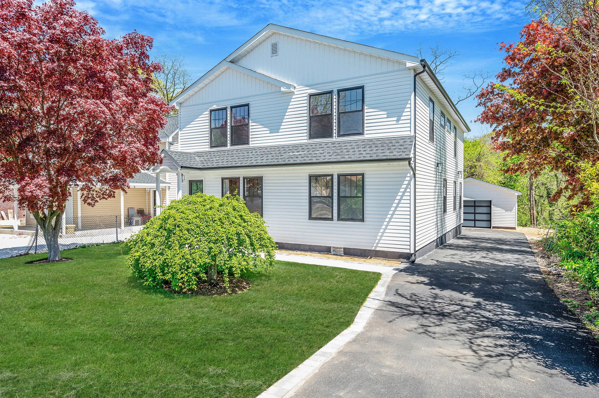 View of front facade with a detached garage, an outbuilding, and a front yard