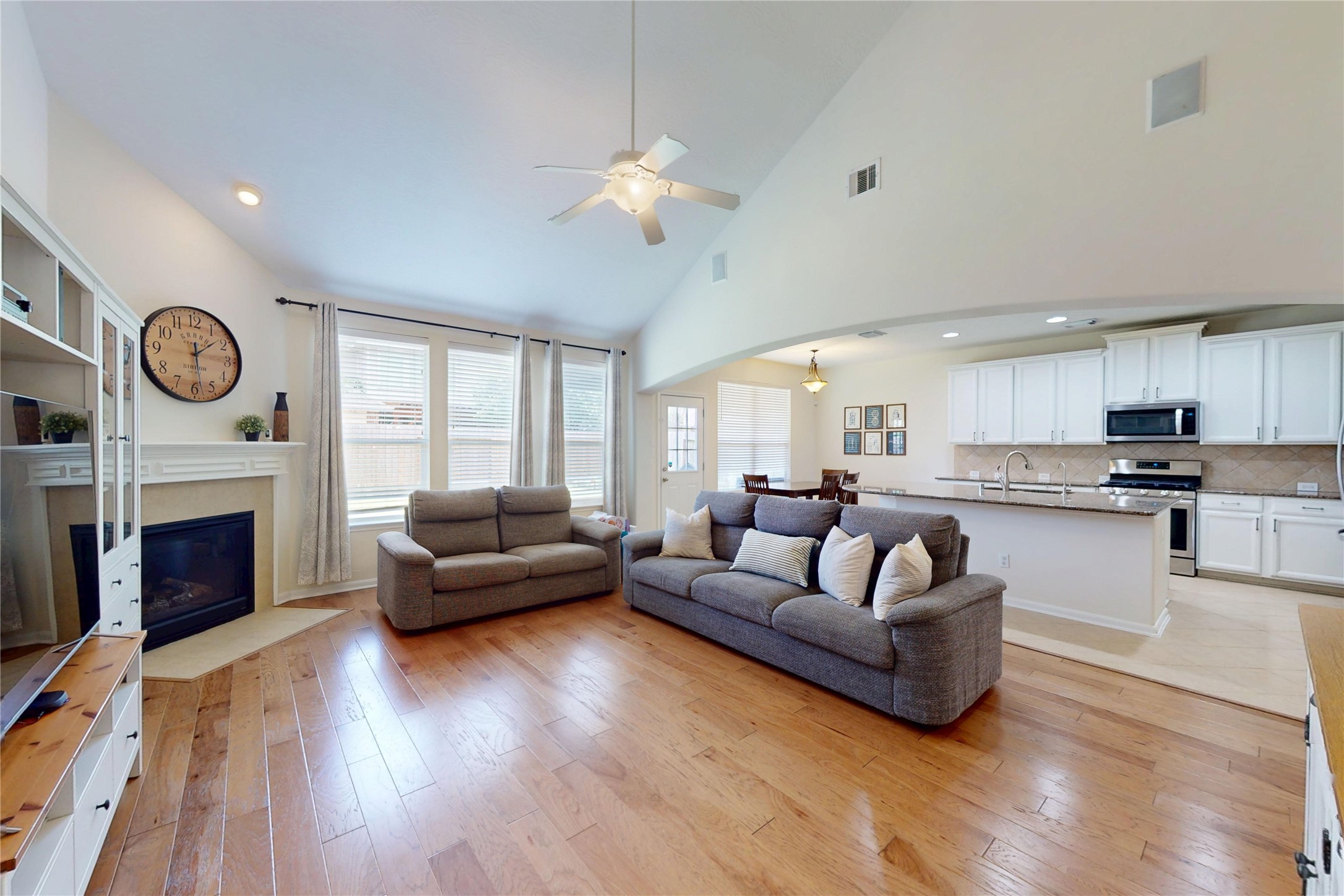 17402 Rainer Valley Lane Humble, TX 77346 - Photo 10 of 33 This spacious living area features high ceilings, a cozy fireplace, and abundant natural light. It seamlessly flows into an open-concept kitchen with modern appliances and a large island, perfect for entertaining.