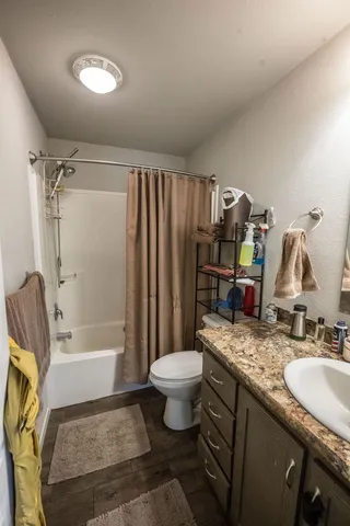 a bathroom with a granite countertop sink toilet and shower