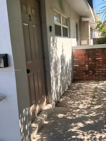 a view of a house with a door and wooden bench