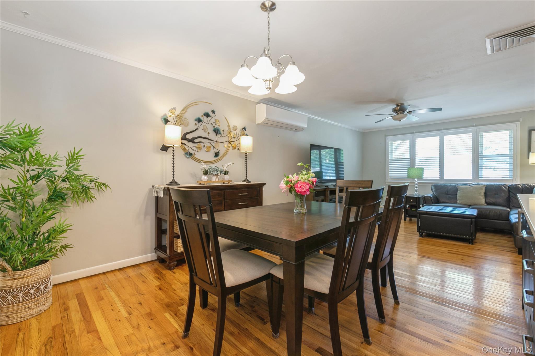 115 Clarendon Road Ronkonkoma, NY 11779 - Photo 9 of 45 Open-concept dining area featuring wood-finish flooring, crown molding, and a contemporary chandelier