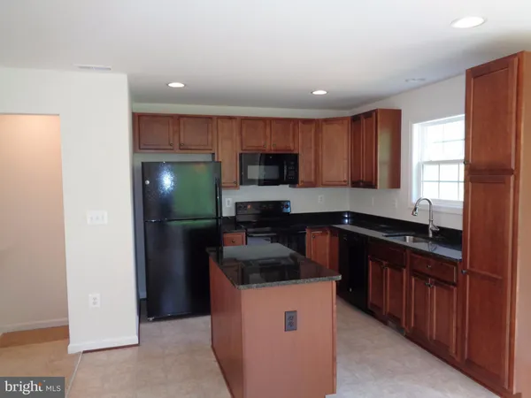 a kitchen with granite countertop a refrigerator stove a sink and dishwasher with wooden cabinets