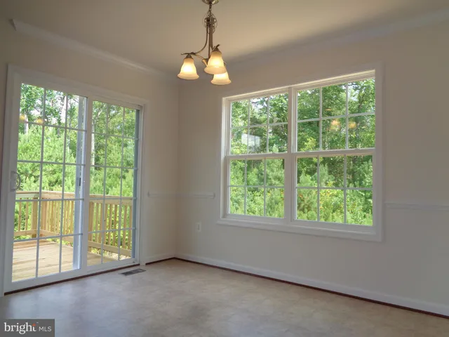 a view of an empty room with windows and chandelier