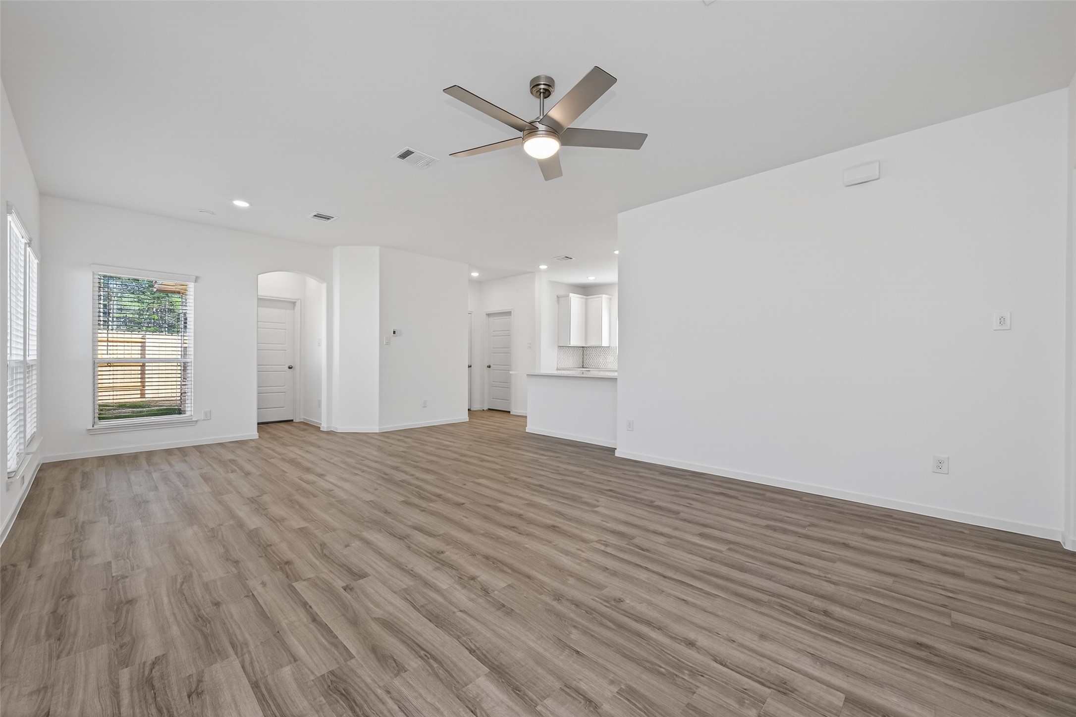 9718 Enclave Ridge Road Willis, TX 77318 - Photo 10 of 34 a view of an empty room with wooden floor and a ceiling fan