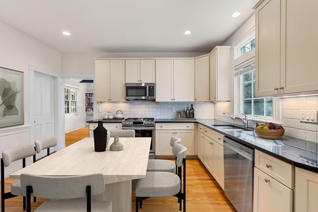 60 Oxford Road Newton, MA 02459 - Photo 13 of 42 a kitchen with a stove a sink a kitchen island with a dining table and chairs