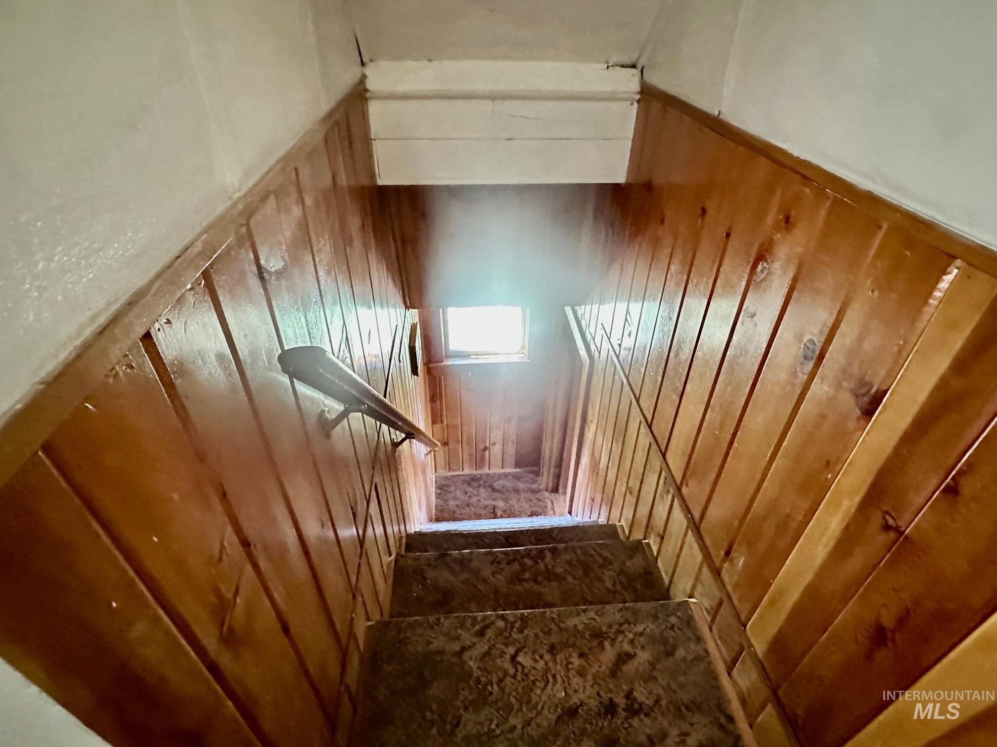 509 Deadline Road, Unit 2 Twin Falls, ID 83301 - Photo 21 of 28 Stairwell featuring wood paneling, a wall-mounted handrail, and carpeted treads