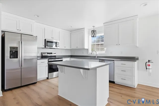 a kitchen with cabinets stainless steel appliances a sink and wooden floor