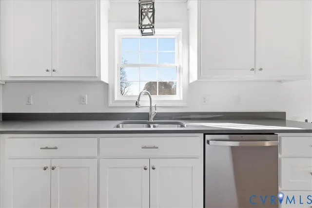 a kitchen with granite countertop white cabinets and a window